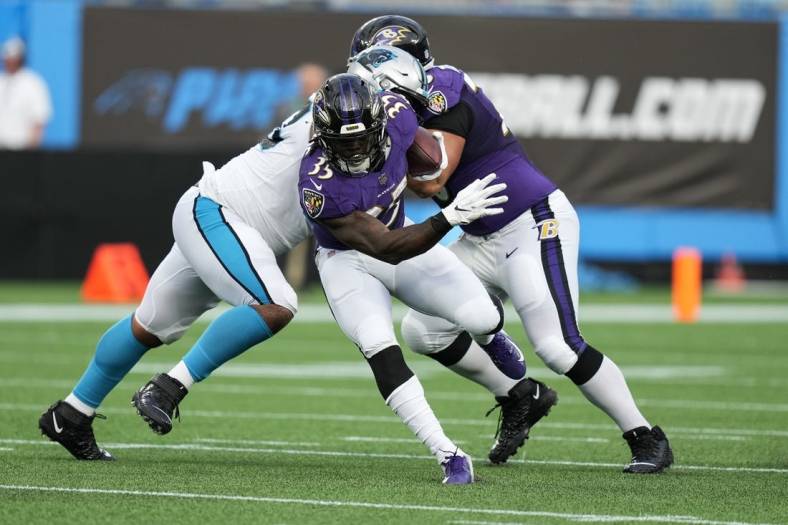 Aug 21, 2021; Charlotte, North Carolina, USA; Baltimore Ravens running back Gus Edwards (35) eludes a tackle by the Carolina Panthers defense for yardage during the first quarter at Bank of America Stadium. Mandatory Credit: Jim Dedmon-USA TODAY Sports