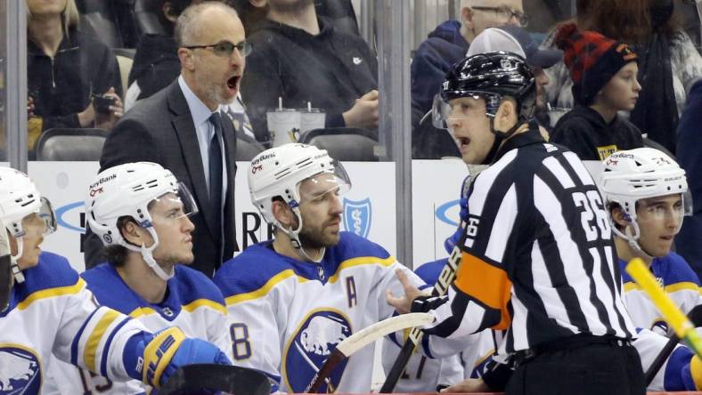 Dec 17, 2021; Pittsburgh, Pennsylvania, USA;  Buffalo Sabres head coach Don Granato (left) reacts to referee Jake Brenk (26) against the Pittsburgh Penguins during the first period at PPG Paints Arena. Mandatory Credit: Charles LeClaire-USA TODAY Sports