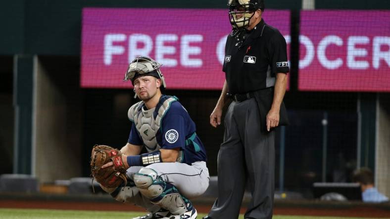 Aug 12, 2022; Arlington, Texas, USA; Seattle Mariners catcher Cal Raleigh (29) looks to the dugout as umpire Jerry Meals (41) looks on in the second inning against the Texas Rangers at Globe Life Field. Mandatory Credit: Tim Heitman-USA TODAY Sports