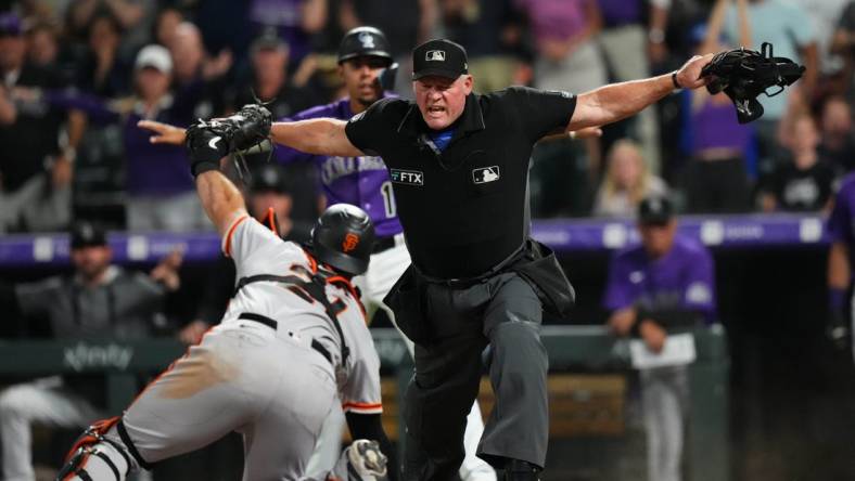 Sep 20, 2022; Denver, Colorado, USA; MLB home plate umpire Ted Barrett (65) signals safe towards San Francisco Giants catcher Joey Bart (21) in the eighth inning against the Colorado Rockies at Coors Field. Mandatory Credit: Ron Chenoy-USA TODAY Sports