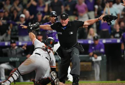 Sep 20, 2022; Denver, Colorado, USA; MLB home plate umpire Ted Barrett (65) signals safe towards San Francisco Giants catcher Joey Bart (21) in the eighth inning against the Colorado Rockies at Coors Field. Mandatory Credit: Ron Chenoy-USA TODAY Sports