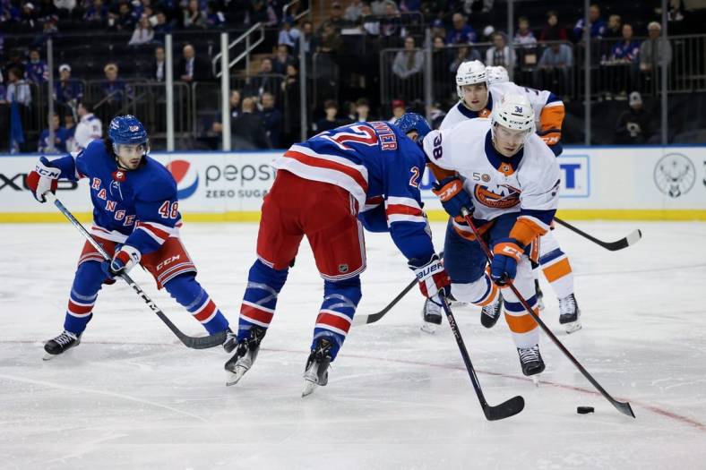 Sep 26, 2022; New York, New York, USA; New York Islanders defenseman Parker Wotherspoon (38) and New York Rangers center Ryan Carpenter (22) battle for the puck as Rangers left wing Adam Sykora (38) watches during the first period at Madison Square Garden. Mandatory Credit: Jessica Alcheh-USA TODAY Sports