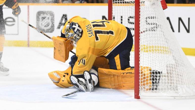 Sep 30, 2022; Nashville, Tennessee, USA;  Tampa Bay Lightning left wing Brandon Hagel (38) slides into Nashville Predators goaltender Juuse Saros (74) during the second period at Bridgestone Arena. Mandatory Credit: Steve Roberts-USA TODAY Sports