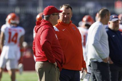 Oct 1, 2022; Madison, Wisconsin, USA;  Illinois Fighting Illini head coach Bret Bielema and Wisconsin Badgers head coach Paul Chryst talk on the field prior to the game at Camp Randall Stadium. Mandatory Credit: Jeff Hanisch-USA TODAY Sports