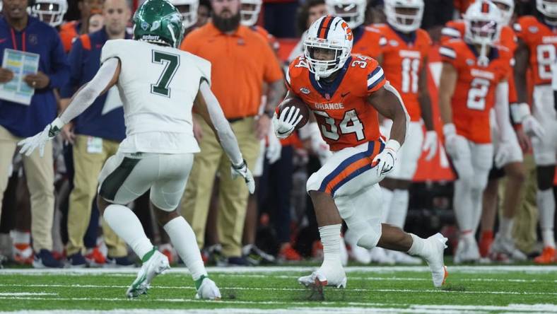 Oct 1, 2022; Syracuse, New York, USA; Syracuse Orange running back Sean Tucker (34) runs with the ball with Wagner Seahawks defensive back Coby Calvin (7) defending during the first half at JMA Wireless Dome. Mandatory Credit: Gregory Fisher-USA TODAY Sports