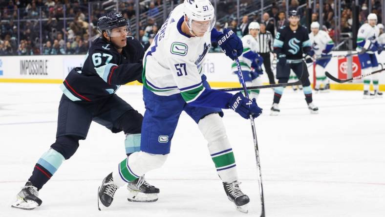 Oct 1, 2022; Seattle, Washington, USA; Vancouver Canucks defenseman Tyler Myers (57) shoots the puck ahead of Seattle Kraken center Morgan Geekie (67) during the second period at Climate Pledge Arena. Mandatory Credit: Joe Nicholson-USA TODAY Sports