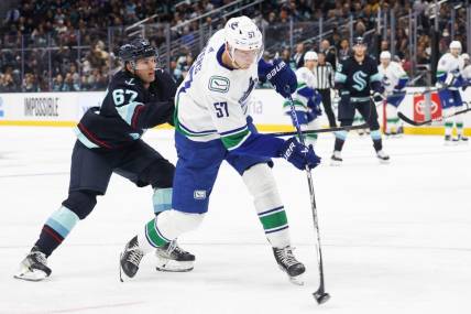 Oct 1, 2022; Seattle, Washington, USA; Vancouver Canucks defenseman Tyler Myers (57) shoots the puck ahead of Seattle Kraken center Morgan Geekie (67) during the second period at Climate Pledge Arena. Mandatory Credit: Joe Nicholson-USA TODAY Sports