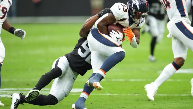 Oct 2, 2022; Paradise, Nevada, USA; Denver Broncos running back Javonte Williams (33) is tackled by Las Vegas Raiders linebacker Denzel Perryman (52) during a game at Allegiant Stadium. Mandatory Credit: Stephen R. Sylvanie-USA TODAY Sports