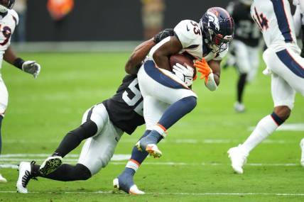 Oct 2, 2022; Paradise, Nevada, USA; Denver Broncos running back Javonte Williams (33) is tackled by Las Vegas Raiders linebacker Denzel Perryman (52) during a game at Allegiant Stadium. Mandatory Credit: Stephen R. Sylvanie-USA TODAY Sports