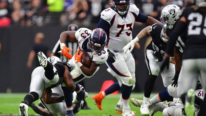 Oct 2, 2022; Paradise, Nevada, USA; Denver Broncos running back Javonte Williams (33) is brought down by Las Vegas Raiders linebacker Denzel Perryman (52) during the first half at Allegiant Stadium. Mandatory Credit: Gary A. Vasquez-USA TODAY Sports