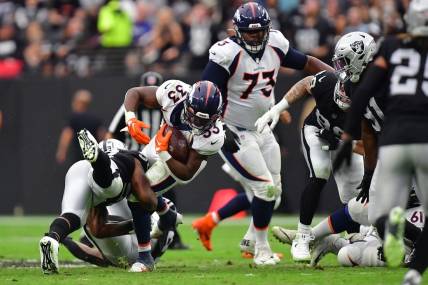 Oct 2, 2022; Paradise, Nevada, USA; Denver Broncos running back Javonte Williams (33) is brought down by Las Vegas Raiders linebacker Denzel Perryman (52) during the first half at Allegiant Stadium. Mandatory Credit: Gary A. Vasquez-USA TODAY Sports