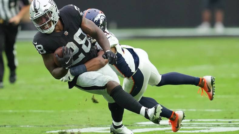 Oct 2, 2022; Paradise, Nevada, USA; Las Vegas Raiders running back Josh Jacobs (28) is tackled by Denver Broncos cornerback K'Waun Williams (21) during a game at Allegiant Stadium. Mandatory Credit: Stephen R. Sylvanie-USA TODAY Sports