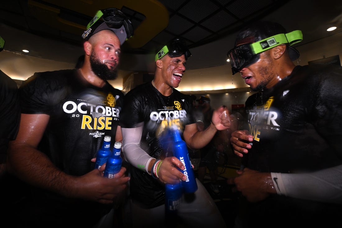 Oct 2, 2022; San Diego, California, USA; San Diego Padres right fielder Juan Soto (center) celebrates in the clubhouse with relief pitcher Luis Garcia (left) and center fielder Jose Azocar (right) following the game against the Chicago White Sox after clinching a playoff berth at Petco Park. Mandatory Credit: Orlando Ramirez-USA TODAY Sports