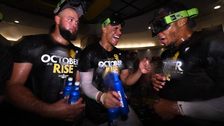 Oct 2, 2022; San Diego, California, USA; San Diego Padres right fielder Juan Soto (center) celebrates in the clubhouse with relief pitcher Luis Garcia (left) and center fielder Jose Azocar (right) following the game against the Chicago White Sox after clinching a playoff berth at Petco Park. Mandatory Credit: Orlando Ramirez-USA TODAY Sports