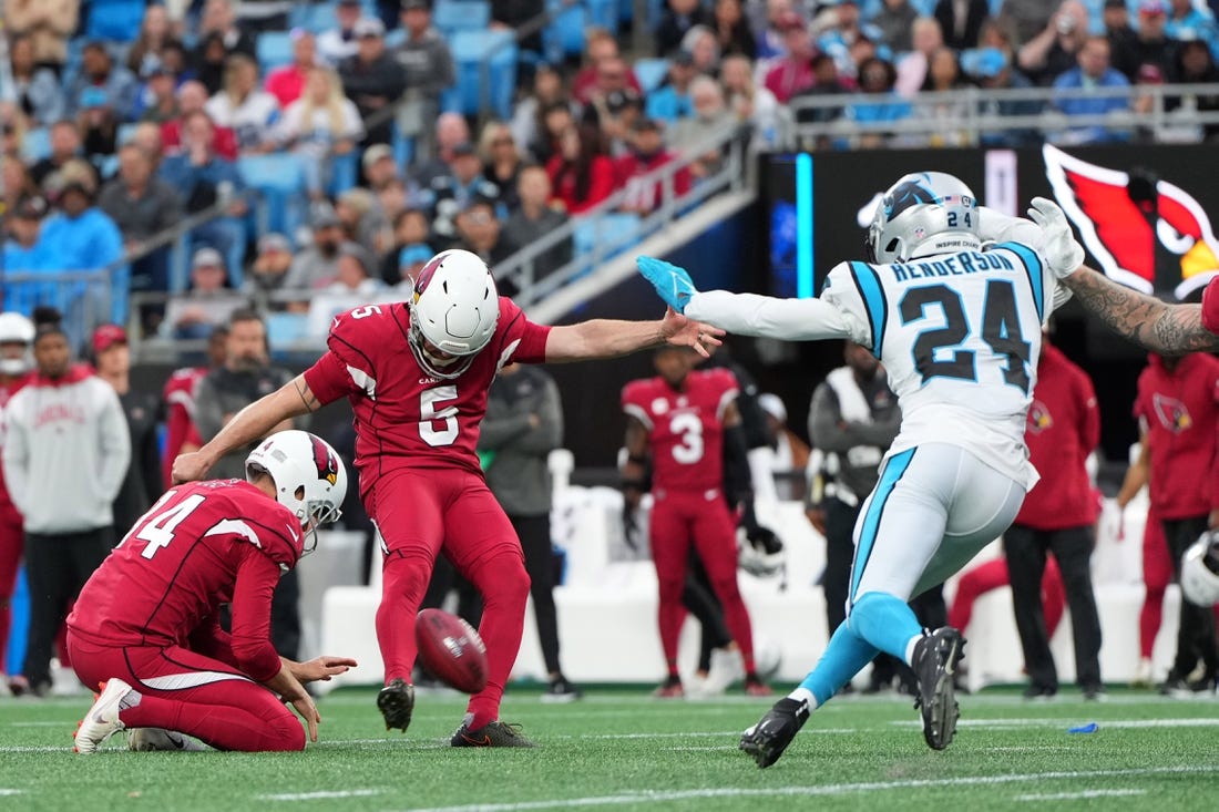 Oct 2, 2022; Charlotte, North Carolina, USA; Arizona Cardinals place kicker Matt Prater (5) kicks a field goal as punter Andy Lee (14) holds and Carolina Panthers cornerback CJ Henderson (24) defends in the fourth quarter at Bank of America Stadium. Mandatory Credit: Bob Donnan-USA TODAY Sports