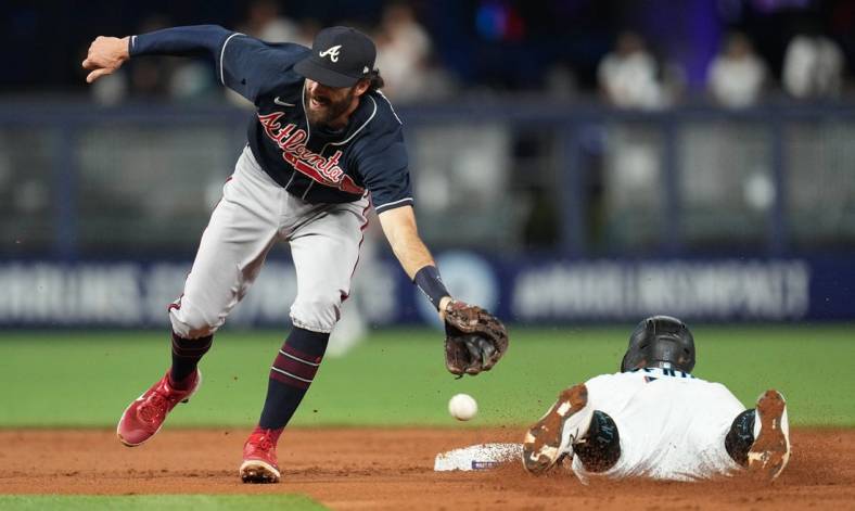 Oct 3, 2022; Miami, Florida, USA; Miami Marlins second baseman Jon Berti (5) steals second base in the first inning as Atlanta Braves shortstop Dansby Swanson (7) reaches for the ball at loanDepot Park. Mandatory Credit: Jim Rassol-USA TODAY Sports
