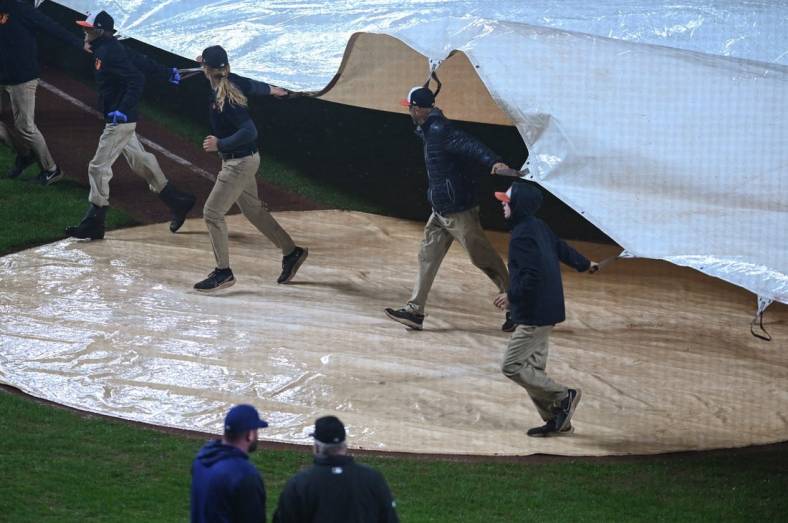 Oct 3, 2022; Baltimore, Maryland, USA; Members of the grounds crew pull a tarp over home plate during a rain delay during the eighth inning of the game between the Baltimore Orioles and the Toronto Blue Jays at Oriole Park at Camden Yards. Mandatory Credit: Tommy Gilligan-USA TODAY Sports