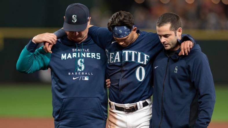 Oct 3, 2022; Seattle, Washington, USA; Seattle Mariners assistant athletic trainer Kevin Orloski and head coach Scott Servais help right fielder Sam Haggerty (0) off the field after Haggerty was injured sliding into second base during the ninth inning against the Detroit Tigers at T-Mobile Park. Detroit defeated Seattle 4-3. Mandatory Credit: Steven Bisig-USA TODAY Sports