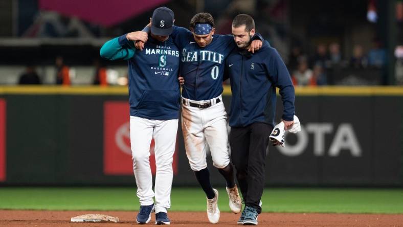 Oct 3, 2022; Seattle, Washington, USA; Seattle Mariners assistant athletic trainer Kevin Orloski and head coach Scott Servais help right fielder Sam Haggerty (0) off the field after Haggerty was injured sliding into second base during the ninth inning against the Detroit Tigers at T-Mobile Park. Detroit defeated Seattle 4-3. Mandatory Credit: Steven Bisig-USA TODAY Sports