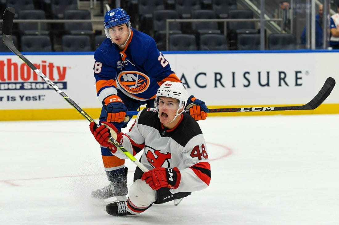 Oct 6, 2022; Elmont, New York, USA; New York Islanders defenseman Alexander Romanov (28) checks New Jersey Devils forward Brian Halonen (46) during the third period at UBS Arena. Mandatory Credit: Dennis Schneidler-USA TODAY Sports