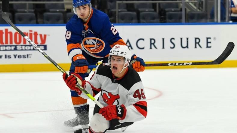 Oct 6, 2022; Elmont, New York, USA; New York Islanders defenseman Alexander Romanov (28) checks New Jersey Devils forward Brian Halonen (46) during the third period at UBS Arena. Mandatory Credit: Dennis Schneidler-USA TODAY Sports