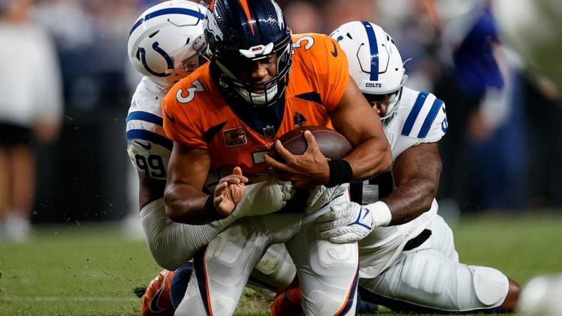 Oct 6, 2022; Denver, Colorado, USA; Denver Broncos quarterback Russell Wilson (3) is tackled by Indianapolis Colts defensive tackle DeForest Buckner (99) and defensive end Yannick Ngakoue (91) in the third quarter at Empower Field at Mile High. Mandatory Credit: Isaiah J. Downing-USA TODAY Sports