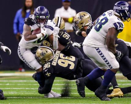 Oct 9, 2022; New Orleans, Louisiana, USA; Seattle Seahawks running back Rashaad Penny (20) is tackled by New Orleans Saints defensive end Carl Granderson (96) and defensive tackle Kentavius Street (91) during the first half at Caesars Superdome. Mandatory Credit: Stephen Lew-USA TODAY Sports