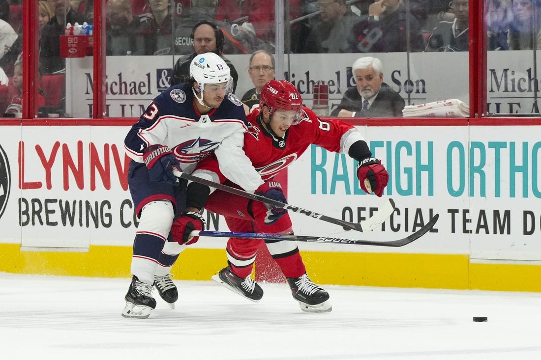 Oct 12, 2022; Raleigh, North Carolina, USA; Columbus Blue Jackets left wing Johnny Gaudreau (13) and Carolina Hurricanes center Jesperi Kotkaniemi (82) battle over the puck during the first period at PNC Arena. Mandatory Credit: James Guillory-USA TODAY Sports