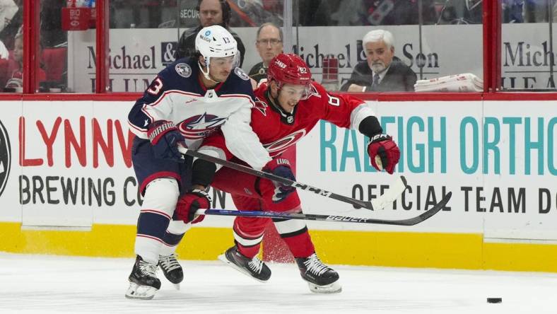 Oct 12, 2022; Raleigh, North Carolina, USA; Columbus Blue Jackets left wing Johnny Gaudreau (13) and Carolina Hurricanes center Jesperi Kotkaniemi (82) battle over the puck during the first period at PNC Arena. Mandatory Credit: James Guillory-USA TODAY Sports