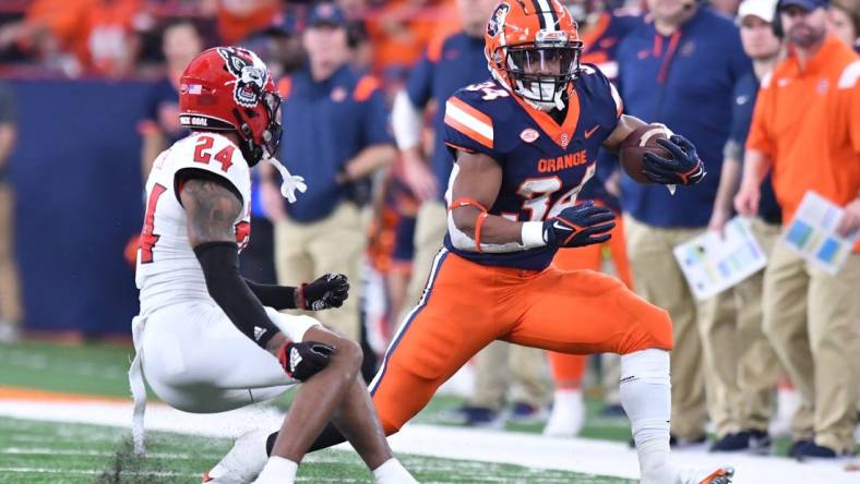 Oct 15, 2022; Syracuse, New York, USA; Syracuse Orange running back Sean Tucker (34) tries to move past North Carolina State Wolfpack cornerback Derrek Pitts Jr. (24) in the second quarter at JMA Wireless Dome. Mandatory Credit: Mark Konezny-USA TODAY Sports