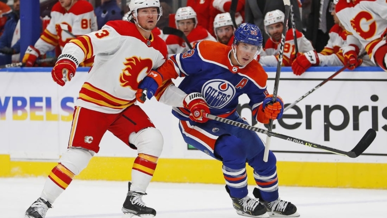 Oct 15, 2022; Edmonton, Alberta, CAN; Edmonton Oilers forward Ryan Nugent-Hopkins (93) and Calgary Flames forward Tyler Toffoli (73) chase a loose puck during the third period at Rogers Place. Mandatory Credit: Perry Nelson-USA TODAY Sports