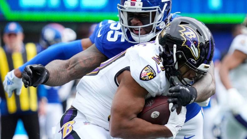 Oct 16, 2022; East Rutherford, New Jersey, USA; Baltimore Ravens running back J.K. Dobbins (27) is tackled by New York Giants linebacker Jihad Ward (55) during the first quarter at MetLife Stadium. Mandatory Credit: Robert Deutsch-USA TODAY Sports