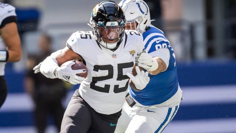 Oct 16, 2022; Indianapolis, Indiana, USA; Jacksonville Jaguars running back James Robinson (25) runs the ball while Indianapolis Colts defensive tackle Grover Stewart (90) defends  in the first quarter at Lucas Oil Stadium. Mandatory Credit: Trevor Ruszkowski-USA TODAY Sports