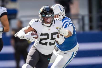 Oct 16, 2022; Indianapolis, Indiana, USA; Jacksonville Jaguars running back James Robinson (25) runs the ball while Indianapolis Colts defensive tackle Grover Stewart (90) defends  in the first quarter at Lucas Oil Stadium. Mandatory Credit: Trevor Ruszkowski-USA TODAY Sports