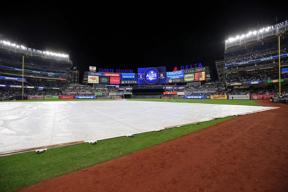 Oct 17, 2022; Bronx, New York, USA; A general view of the tarp on the field as the video board indicates a delay in game five of the ALDS for the 2022 MLB Playoffs between the New York Yankees and the Cleveland Guardians at Yankee Stadium. Mandatory Credit: Brad Penner-USA TODAY Sports