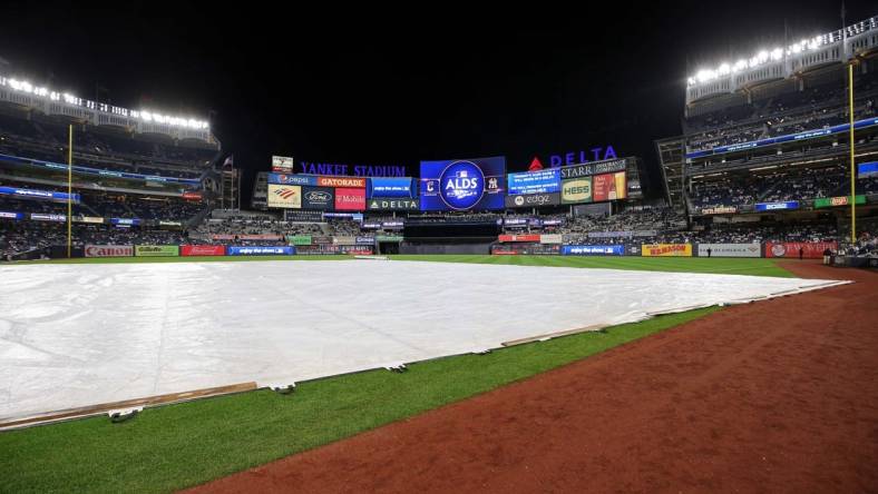 Oct 17, 2022; Bronx, New York, USA; A general view of the tarp on the field as the video board indicates a delay in game five of the ALDS for the 2022 MLB Playoffs between the New York Yankees and the Cleveland Guardians at Yankee Stadium. Mandatory Credit: Brad Penner-USA TODAY Sports