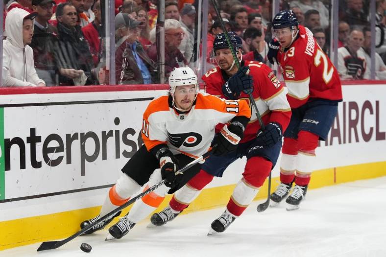 Oct 19, 2022; Sunrise, Florida, USA; Philadelphia Flyers right wing Travis Konecny (11) controls the puck away form Florida Panthers center Sam Reinhart (13) and center Carter Verhaeghe (23) during the second period at FLA Live Arena. Mandatory Credit: Jasen Vinlove-USA TODAY Sports