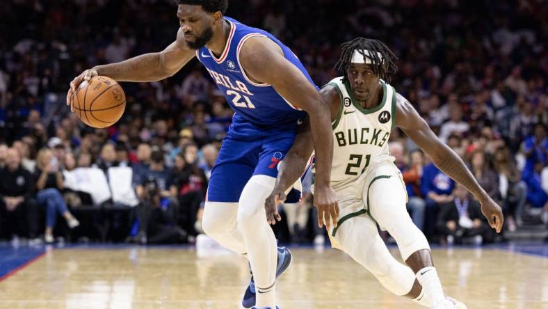 Oct 20, 2022; Philadelphia, Pennsylvania, USA; Philadelphia 76ers center Joel Embiid (21) is tripped up and fouled by Milwaukee Bucks guard Jrue Holiday (21) during the second quarter at Wells Fargo Center. Mandatory Credit: Bill Streicher-USA TODAY Sports