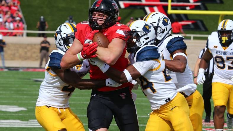 Oct 22, 2022; Lubbock, Texas, USA;  Texas Tech Red Raiders tight end Mason Tharp (80) is tackled by West Virginia Mountaineers defensive safety Marcis Floyd (24), defensive corner back Rashad Ajayi (4) and defensive linebacker Jasir Cox (7) in the first half at Jones AT&T Stadium and Cody Campbell Field. Mandatory Credit: Michael C. Johnson-USA TODAY Sports