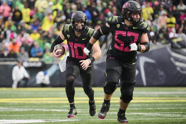 Oct 22, 2022; Eugene, Oregon, USA; Oregon Ducks quarterback Bo Nix (10) carries the football during the second half with help from offensive lineman Ryan Walk (53) against the UCLA Bruins at Autzen Stadium. The Ducks won the game 45-30. Mandatory Credit: Troy Wayrynen-USA TODAY Sports
