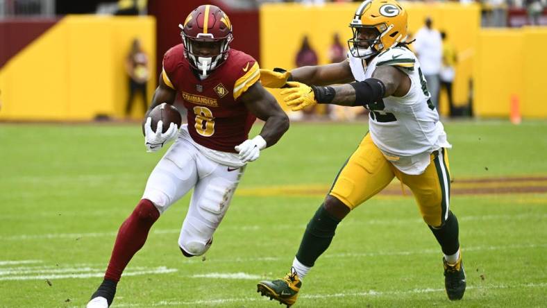 Oct 23, 2022; Landover, Maryland, USA; Washington Commanders running back Brian Robinson Jr. (8) runs past Green Bay Packers linebacker Rashan Gary (52) during the first half at FedExField. Mandatory Credit: Brad Mills-USA TODAY Sports