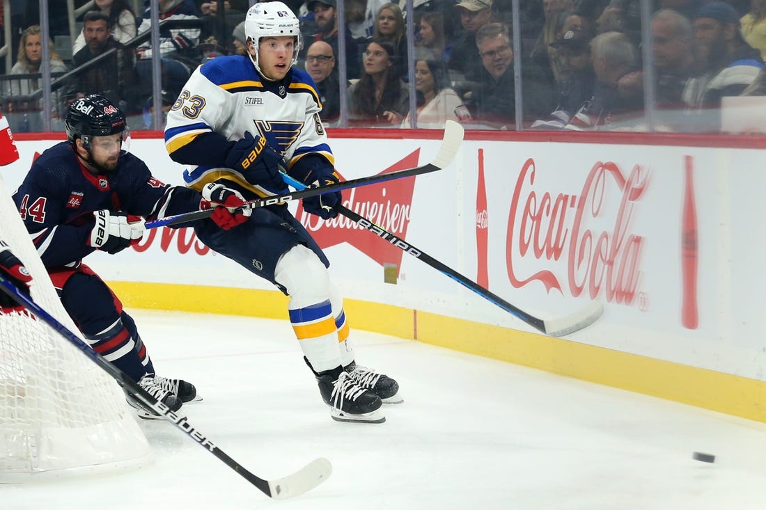 Oct 24, 2022; Winnipeg, Manitoba, CAN;  St. Louis Blues forward Jake Neighbours (63) and Winnipeg Jets defenseman Josh Morrissey (44) chase after the puck during the first period at Canada Life Centre. Mandatory Credit: Terrence Lee-USA TODAY Sports