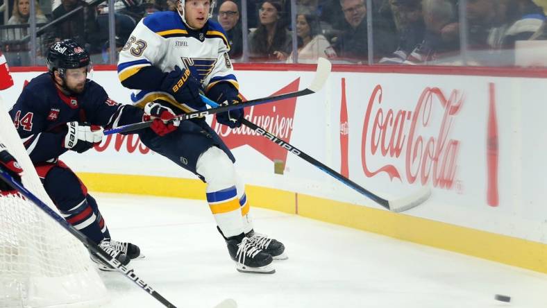 Oct 24, 2022; Winnipeg, Manitoba, CAN;  St. Louis Blues forward Jake Neighbours (63) and Winnipeg Jets defenseman Josh Morrissey (44) chase after the puck during the first period at Canada Life Centre. Mandatory Credit: Terrence Lee-USA TODAY Sports