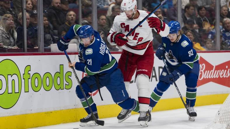 Oct 24, 2022; Vancouver, British Columbia, CAN; Carolina Hurricanes forward Jordan Staal (11) and Vancouver Canucks forward Vasily Podkolzin (92) watch forward Nils Hoglander (21) handle the puck in the first period at Rogers Arena. Mandatory Credit: Bob Frid-USA TODAY Sports