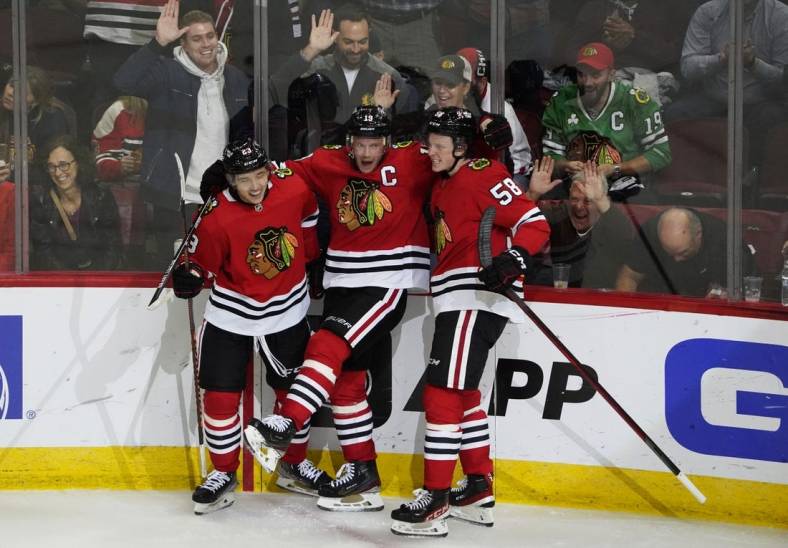 Oct 25, 2022; Chicago, Illinois, USA; Chicago Blackhawks center Philipp Kurashev (23) celebrates his goal with center Jonathan Toews (19) and right wing MacKenzie Entwistle (58) during the second period  at United Center. Mandatory Credit: David Banks-USA TODAY Sports