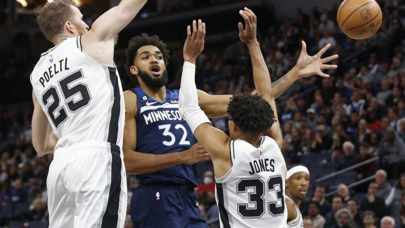 Oct 26, 2022; Minneapolis, Minnesota, USA; Minnesota Timberwolves center Karl-Anthony Towns (32) passes the ball away from the defense of San Antonio Spurs center Jakob Poeltl (25) and guard Tre Jones (33) in the fourth quarter at Target Center. Mandatory Credit: Bruce Kluckhohn-USA TODAY Sports