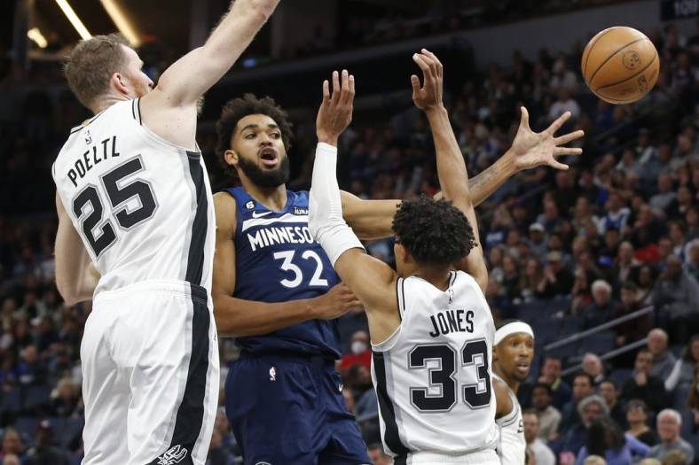 Oct 26, 2022; Minneapolis, Minnesota, USA; Minnesota Timberwolves center Karl-Anthony Towns (32) passes the ball away from the defense of San Antonio Spurs center Jakob Poeltl (25) and guard Tre Jones (33) in the fourth quarter at Target Center. Mandatory Credit: Bruce Kluckhohn-USA TODAY Sports