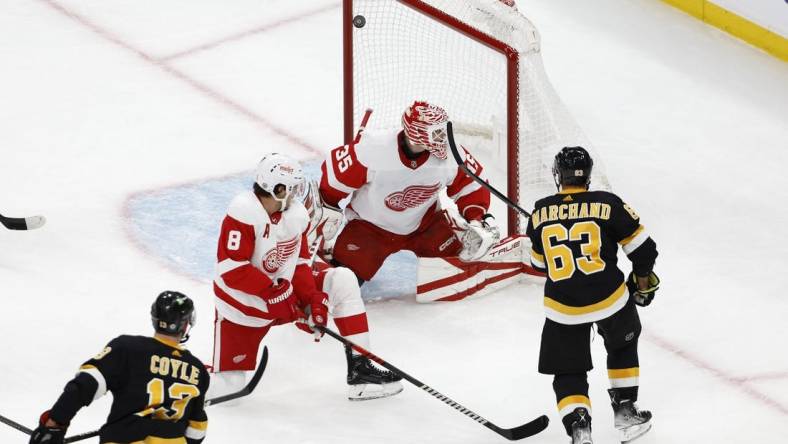 Oct 27, 2022; Boston, Massachusetts, USA; Boston Bruins center Charlie Coyle (13) scores on Detroit Red Wings goaltender Ville Husso (35) as left wing Brad Marchand (63) looks on during the first period at TD Garden. Mandatory Credit: Winslow Townson-USA TODAY Sports