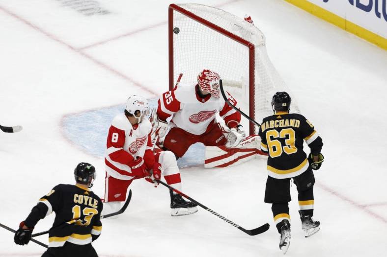 Oct 27, 2022; Boston, Massachusetts, USA; Boston Bruins center Charlie Coyle (13) scores on Detroit Red Wings goaltender Ville Husso (35) as left wing Brad Marchand (63) looks on during the first period at TD Garden. Mandatory Credit: Winslow Townson-USA TODAY Sports