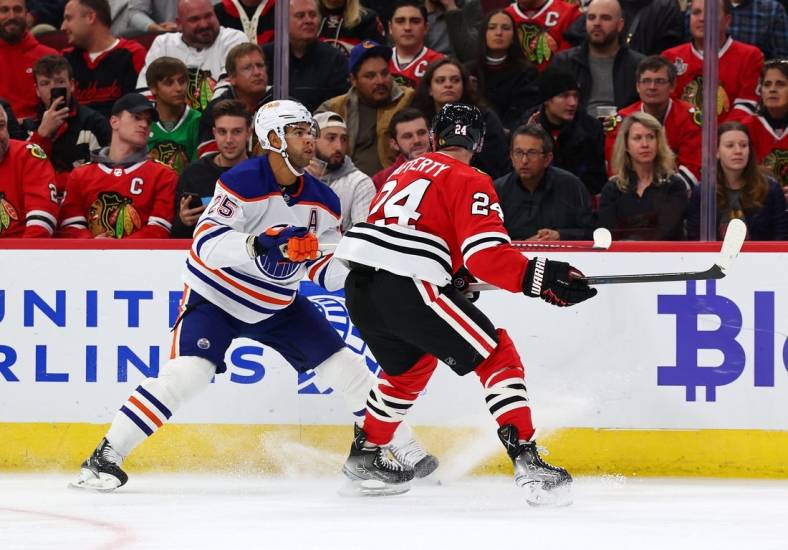 Oct 27, 2022; Chicago, Illinois, USA; Edmonton Oilers defenseman Darnell Nurse (25) skates with the puck against Chicago Blackhawks center Sam Lafferty (24) during the first period at the United Center. Mandatory Credit: Mike Dinovo-USA TODAY Sports